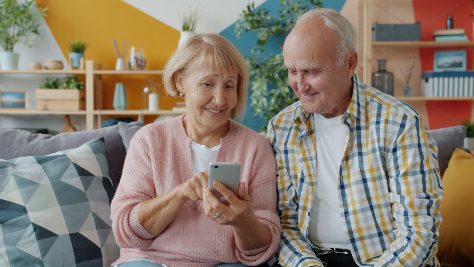 Senior couple using a smartphone together in their living room